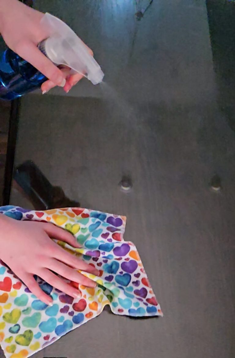 Person spraying a colorful cloth on a surface for cleaning.